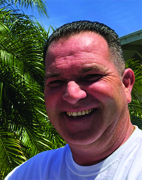 Photo of Jimmy McQuade, with Florida palm trees behind him.